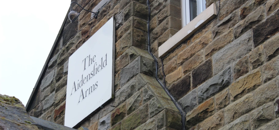 Sign for The Aidensfield Arms on a stone building wall.