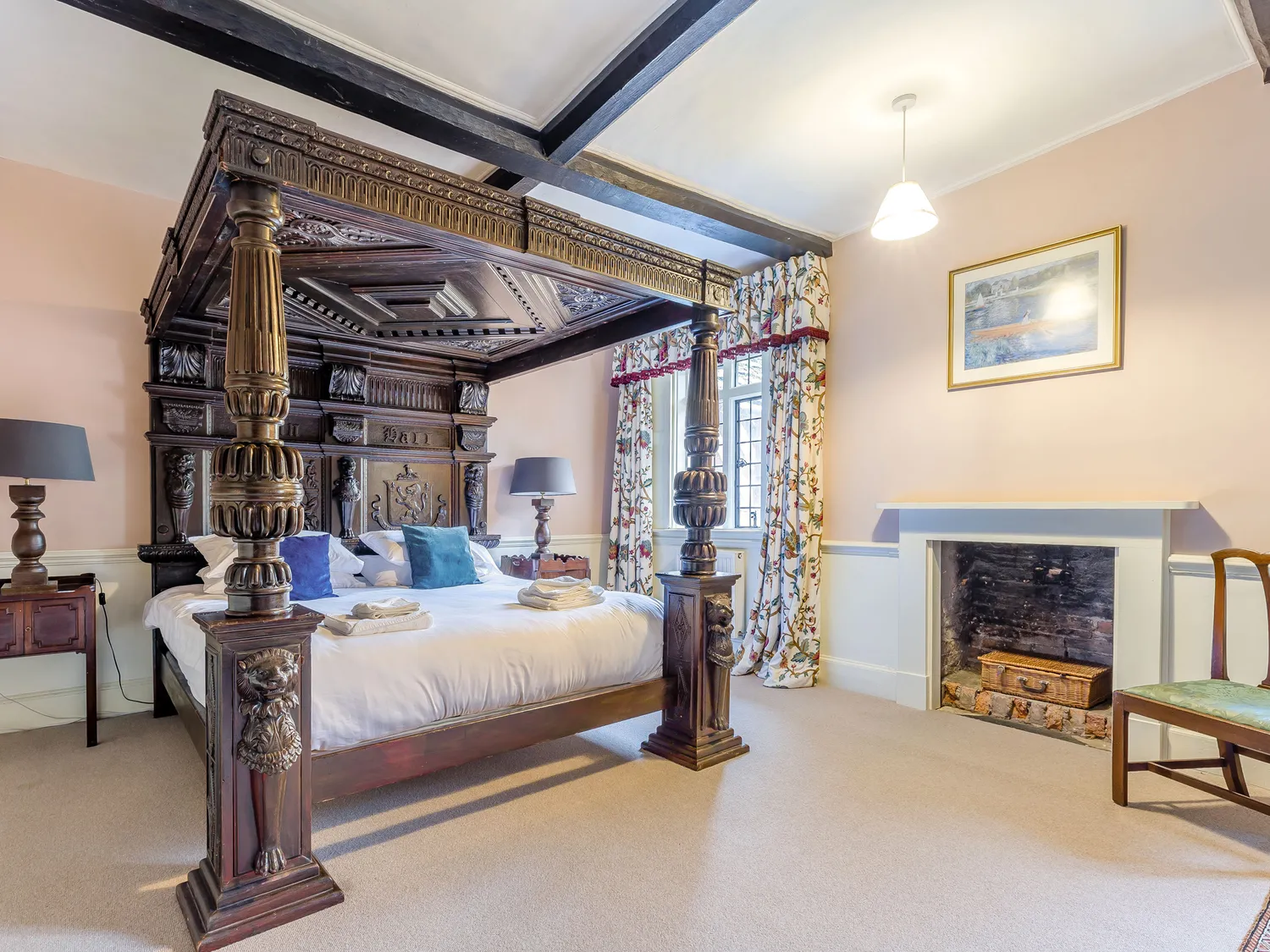 Luxurious bedroom with ornate four-poster bed, elegant decor, and cozy fireplace.