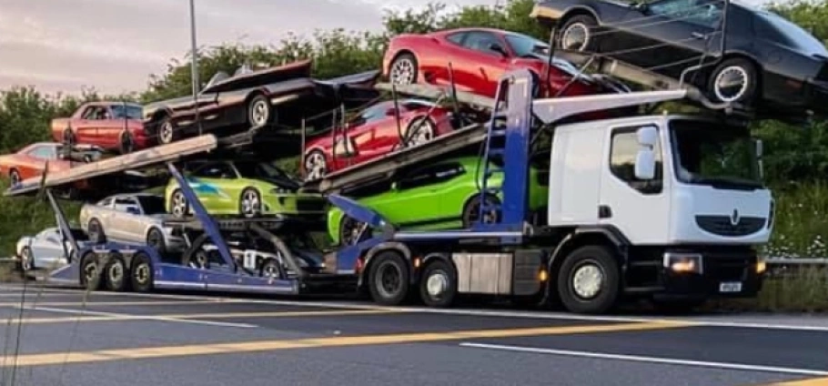 Car transporter truck carrying multiple sports cars on a highway