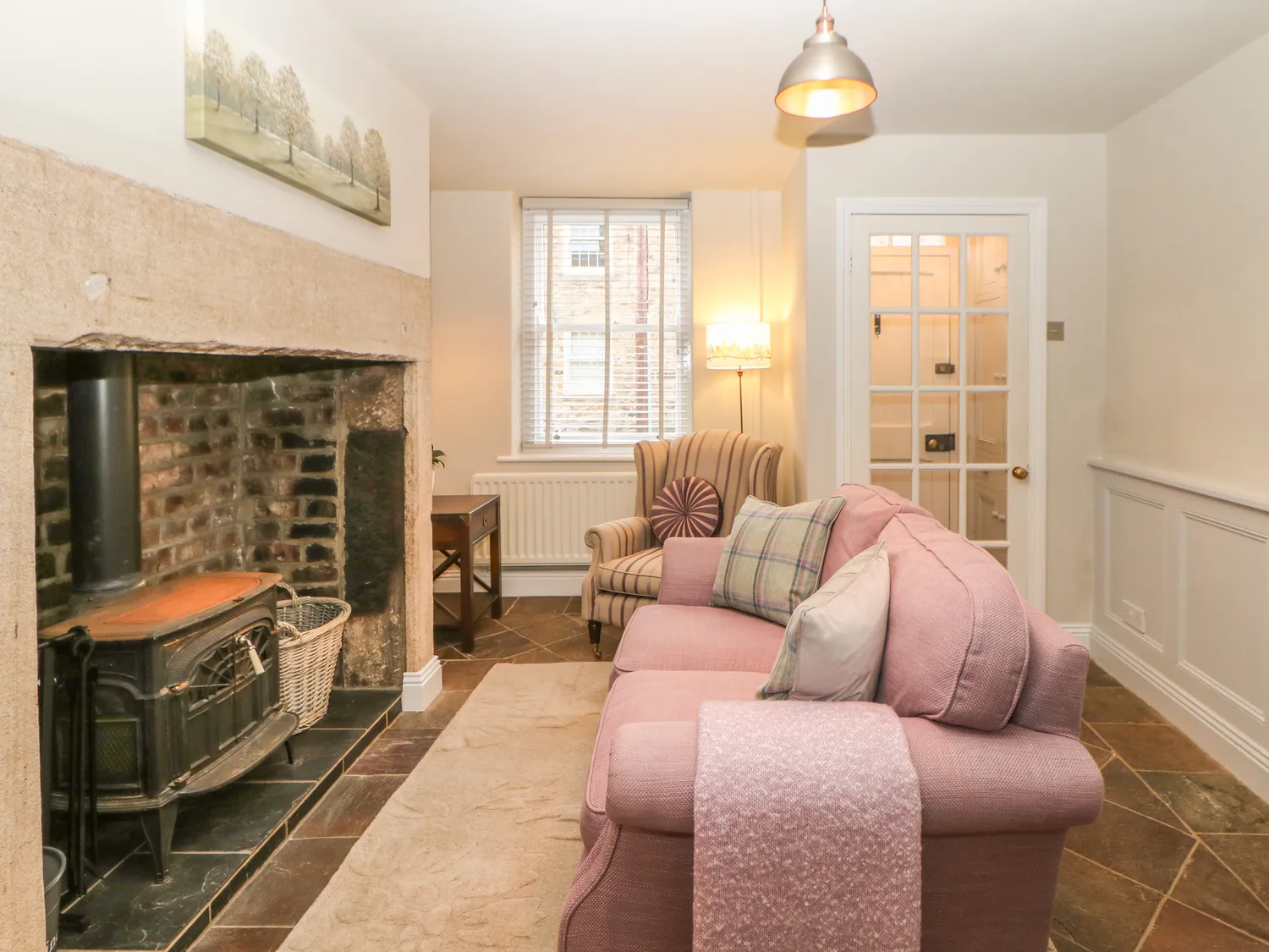 A cosy living room with a stone fireplace, and plush sofas at Chapel Cottage, Corbridge.